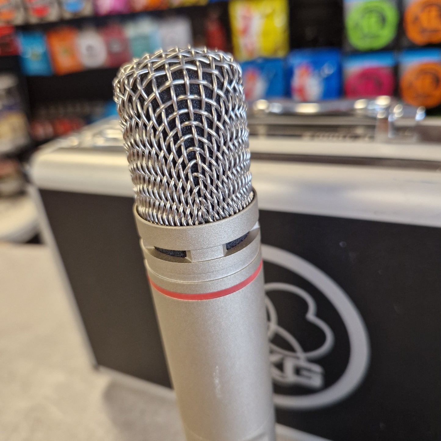 AKG C1000S Close-up of a microphone with a blurred background featuring colorful boxes.