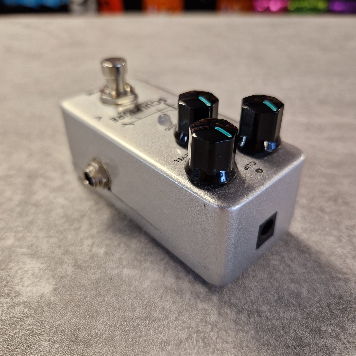 Guitar effects pedal with three knobs on a gray surface