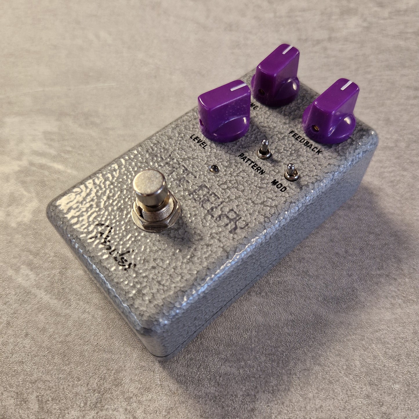 Fender Hammertone Space Delay Silver guitar effects pedal with purple knobs on a beige surface