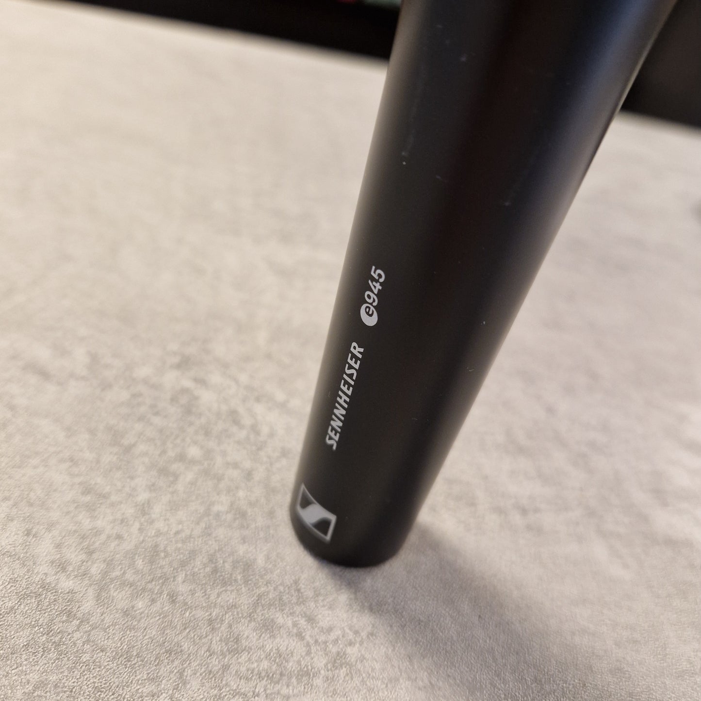 Pre-Owned Sennheiser E935 Close-up of a black cylindrical object with 'Sennheiser' branding on a light grey background