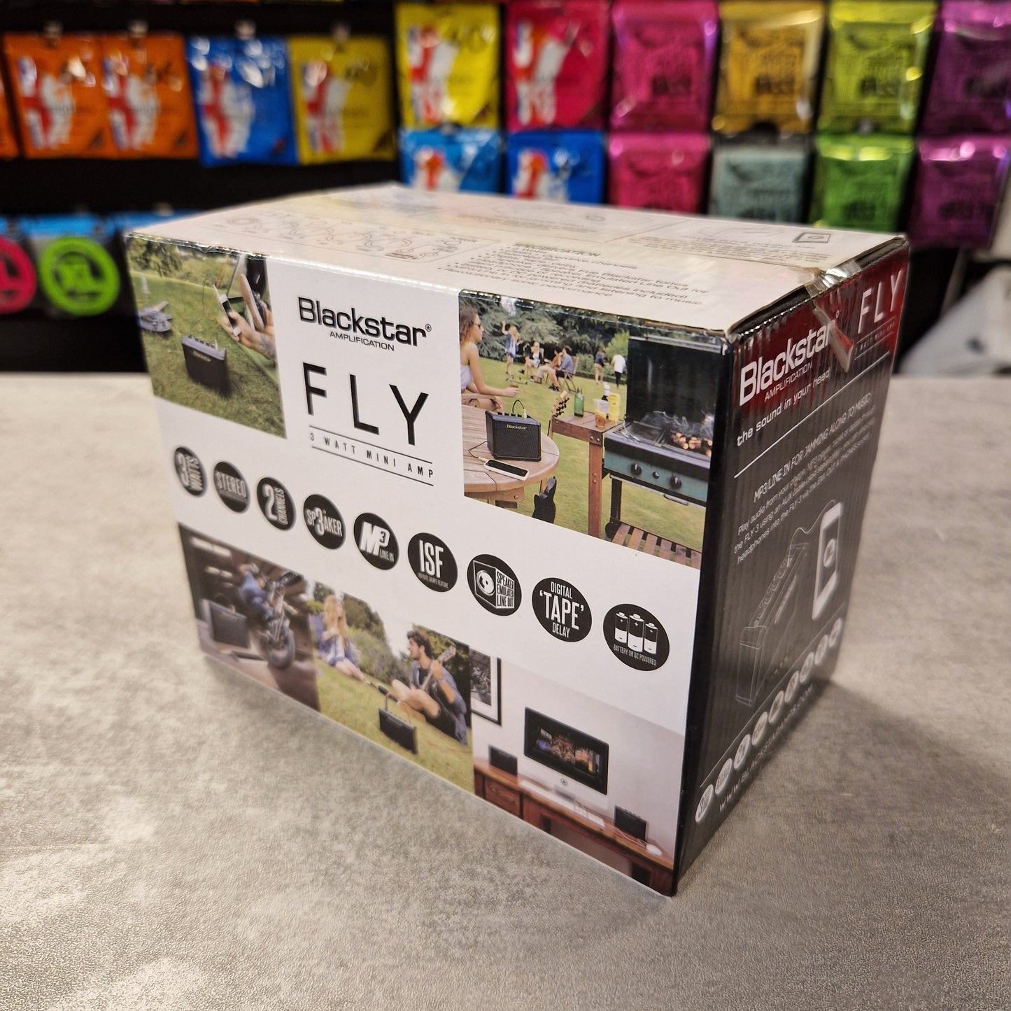 Pre-Owned Blackstar Blackstar Fly guitar amplifier box on a gray surface with colorful packaging in the background