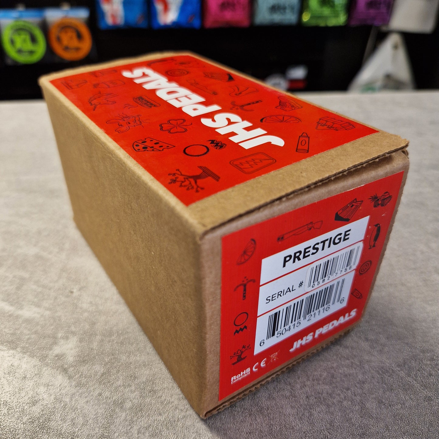 Pre-Owned JHS Cardboard box with red label and 'JHS Pedals' branding on a gray surface.
