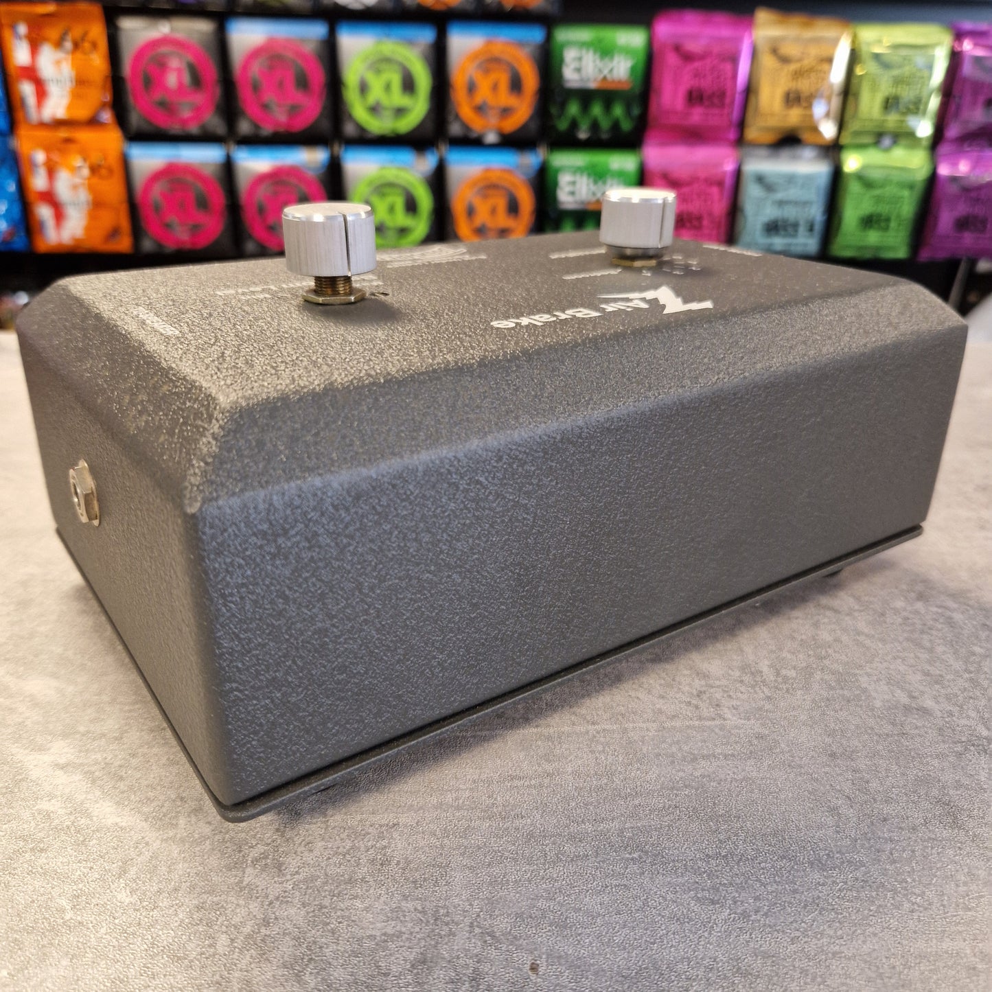 Pre-Owned Dr. Z Trainwreck Gray guitar effects pedal on a concrete floor with colorful boxes in the background