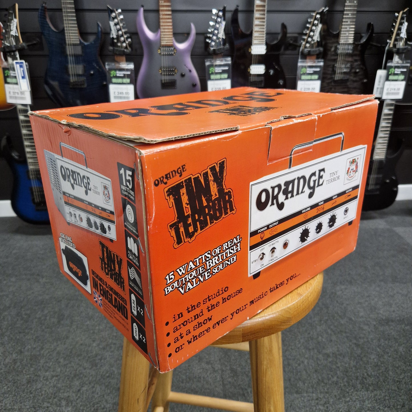 Pre-Owned Orange TT15H Orange amplifier box on a chair with guitars in the background