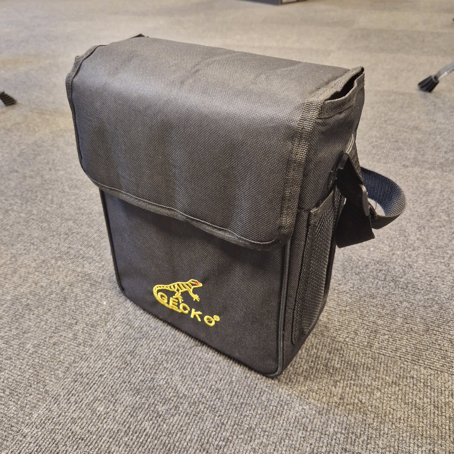 Pre-Owned Gecko C-68Z Black bag with a yellow logo on a gray carpet