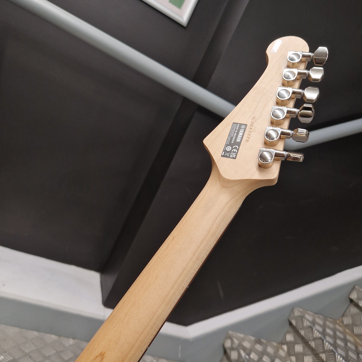 Pre-Owned Yamaha Pacifica 311H Electric - Red Metallic Close-up of an electric guitar headstock and neck, showing a light natural wood finish and silver tuning pegs against a dark indoor background.