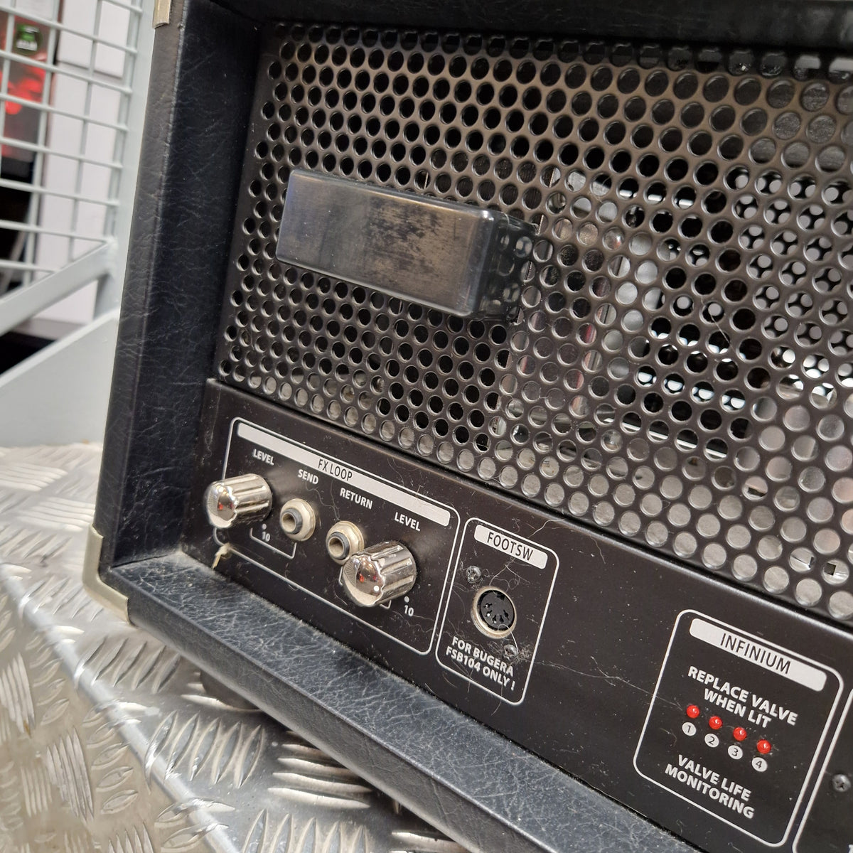 Pre-Owned Bugera 333XL Infinium 120w Electric Amplifer Head Close-up of the rear panel of a black vintage-style speaker amplifier or speaker cabinet, showing a perforated metal grille, control knobs, and a Neumann microphone input jack labeled 'NEUMANN'.