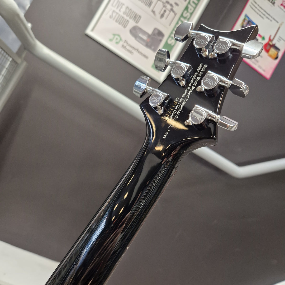 Pre-Owned PRS SE Custom 22 Semi-Hollow Electric Korean - Grey Black Close-up of the headstock of a black electric guitar, showing six silver tuning pegs and white printed brand text that reads 'BUTTE HOLE MUSIC SUPPLY CO. FREDERICKSBURG, TX 75401'.
