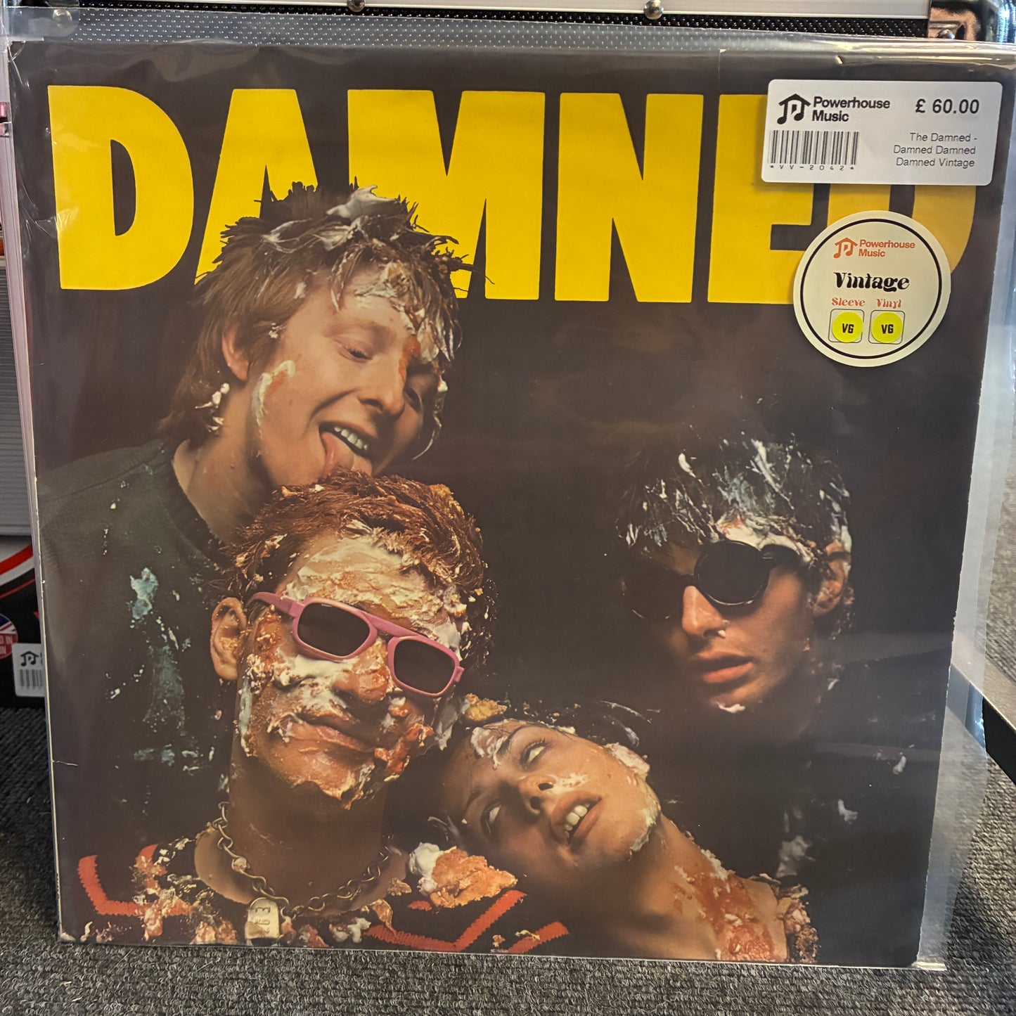 The Damned - Damned Damned Damned Vintage Vinyl LP Damned III vinyl record cover in a clear plastic sleeve, showing the band members covered in white powder with large yellow 'DAMNED' text across the top. A Powerhouse Records price sticker is visible in the upper right.