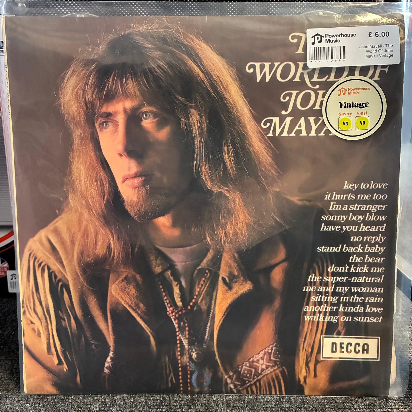 John Mayall - The World Of John Mayall Vintage Vinyl LP Vintage John Mayall 'The World of John Mayall' vinyl record album cover, showing a portrait of the musician with long brown hair and a fringed jacket, with white text and a DECCA logo.