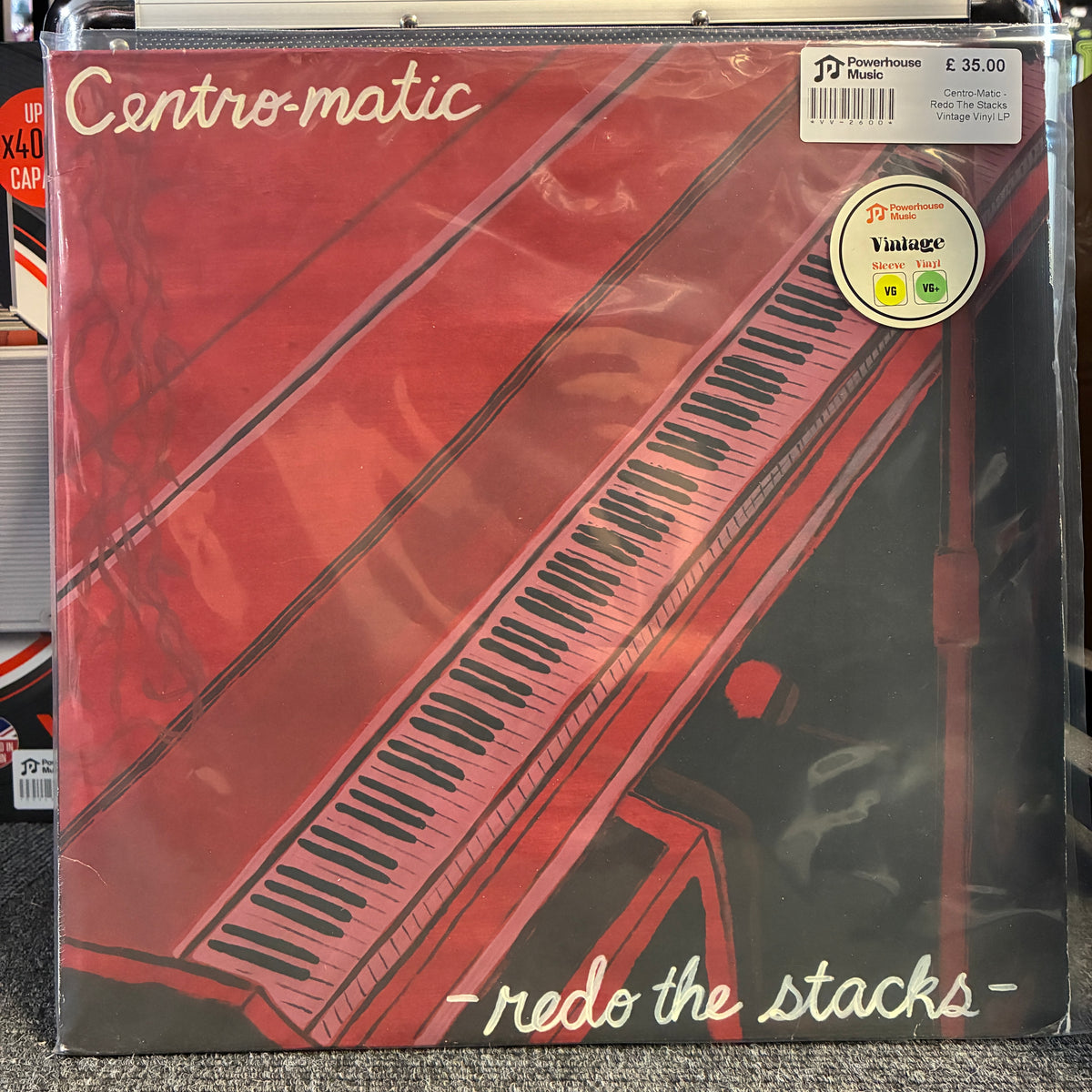 Centro-Matic - Redo The Stacks Vintage Vinyl LP A vinyl record sleeve for the album 'redo the stacks' by Centro-matic, featuring a red piano keyboard illustration. The record is sealed in plastic and shows a JD Powerhouse Music sticker and a Vintage Vinyl sticker.