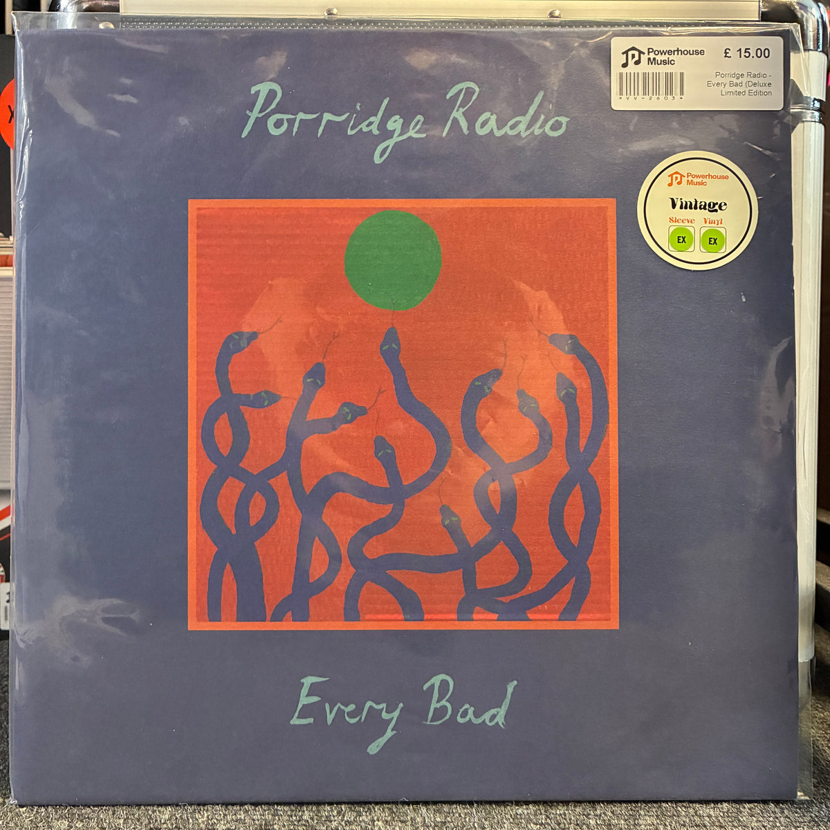 Porridge Radio - Every Bad (Deluxe Limited Edition Flame Orange) Vintage Vinyl LP A vinyl record sleeve for Porridge Radio's 'Every Bad', featuring a dark slate blue background with an orange square graphic containing blue abstract figures and a green circle. The record is sealed in plastic and has a 'Powerhouse Records' sticker on the top right.