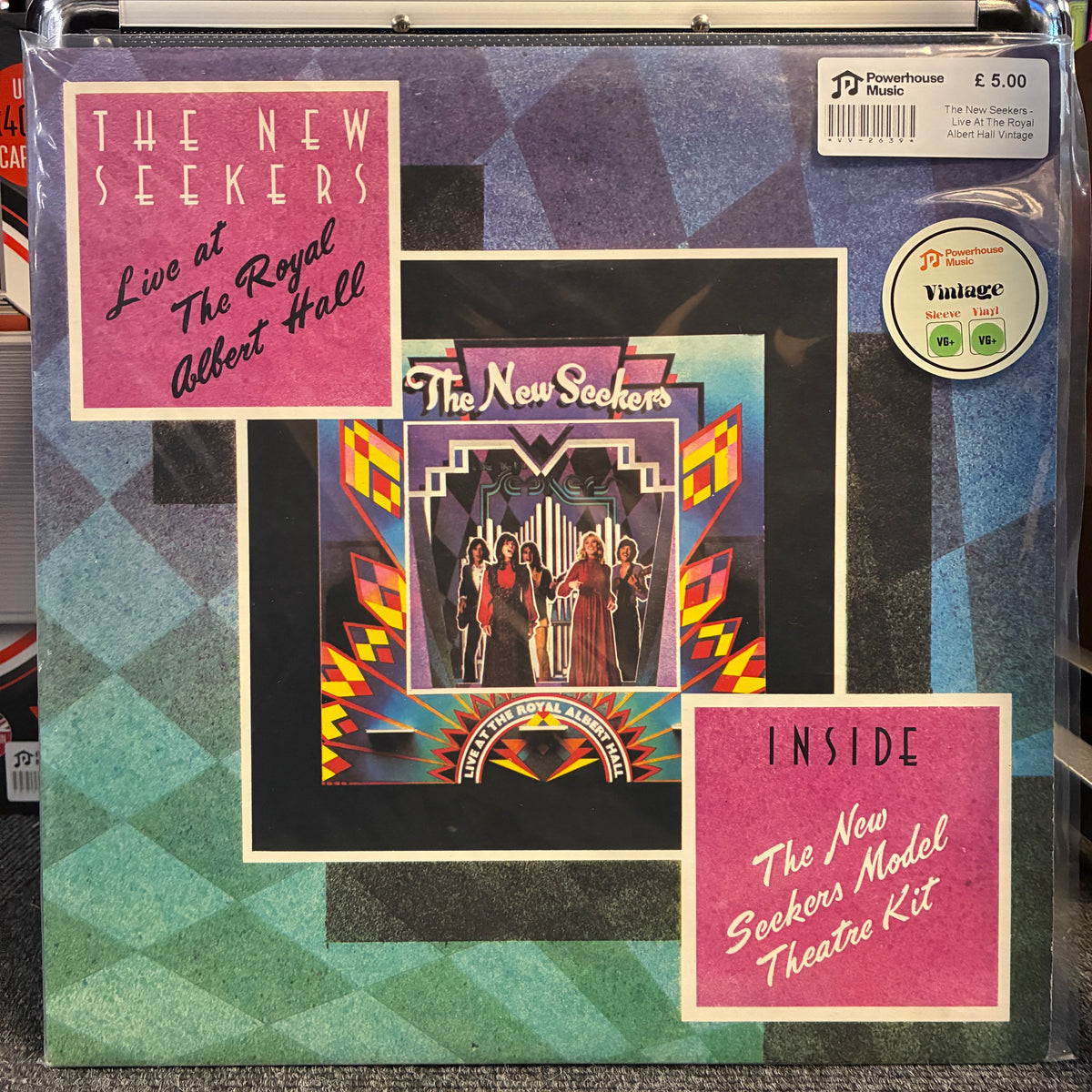 The New Seekers - Live At The Royal Albert Hall Vintage Vinyl LP The New Seekers 'Live at The Royal Albert Hall' vinyl record album cover with a framed collage design, showing the band performing in front of a grand organ. The cover includes pink inset panels reading 'The New Seekers Live at The Royal Albert Hall' and 'Inside The New Seekers Model Theatre Kit,' plus a Yachtage sticker and a barcode price label.
