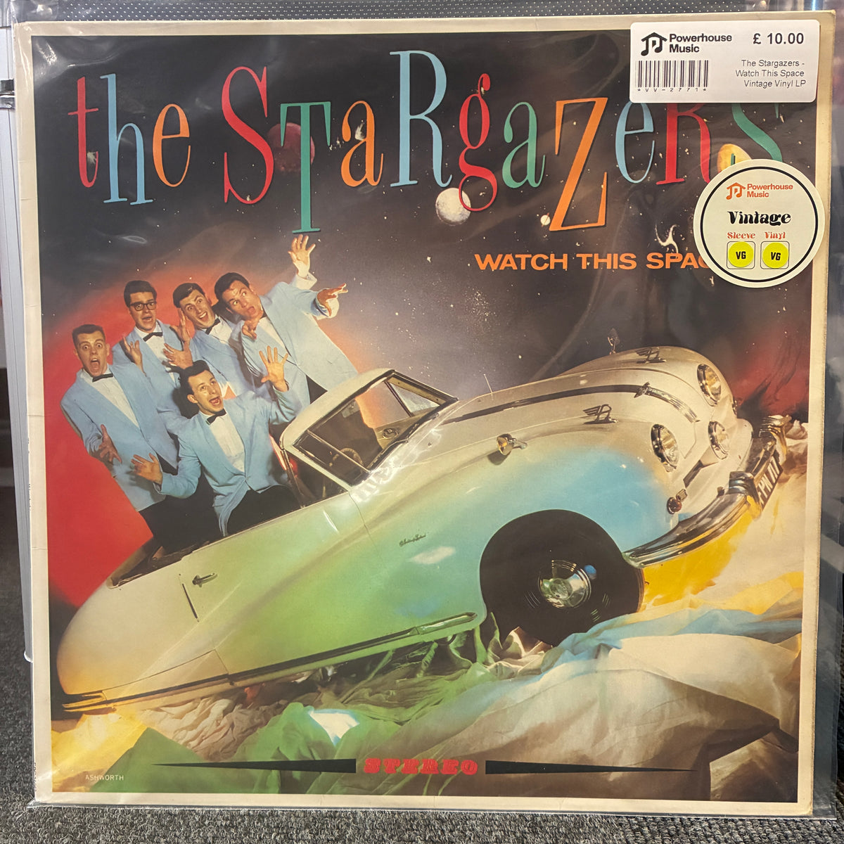 The Stargazers - Watch This Space Vintage Vinyl LP The Spargazen 'Watch This Space' vinyl record album cover, featuring a retro illustration of a car and the group, shown in its shrink wrap on a dark textured surface.