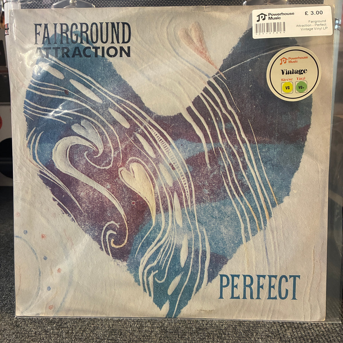 Fairground Attraction - Perfect Vintage Vinyl LP A vinyl record sleeve for Fairground Attraction's 'Perfect' album, sealed in plastic with a visible 'Vintage Record Store' sticker and a barcode price label in the top right. The sleeve features an abstract heart-shaped design in blue, purple, and cream swirls, with the band name and album title printed in dark blue.