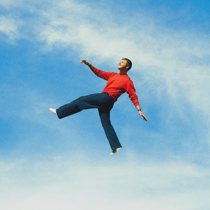 Alex Warren - WILDCHILD (Orange) Vinyl Person in a red sweater and blue jeans floating against a blue sky with white clouds