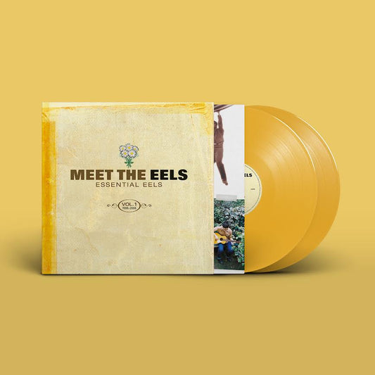 EELS - Meet The EELS: Essential EELS Vol. 1 1996-2006 (Yellow Gold) Vinyl A vinyl record album for 'Meet The Eels - Essential Eels Vol. 1' shown with its illustrated sleeve and a translucent golden-yellow record on a solid mustard-yellow background.