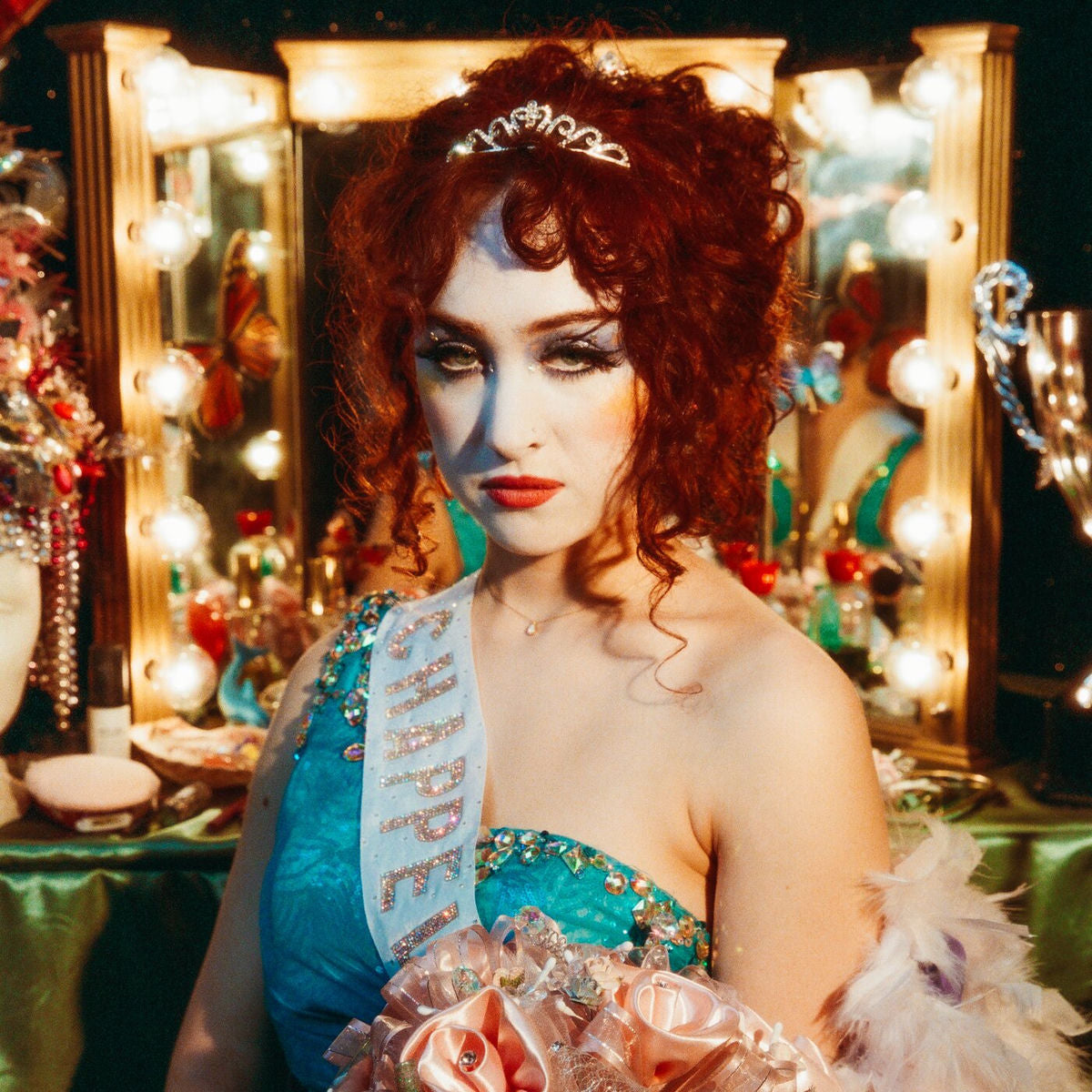 Chappell Roan - The Rise and Fall of a Midwest Princess Vinyl Woman in a theatrical costume with makeup and a sash in front of a mirror with lights.