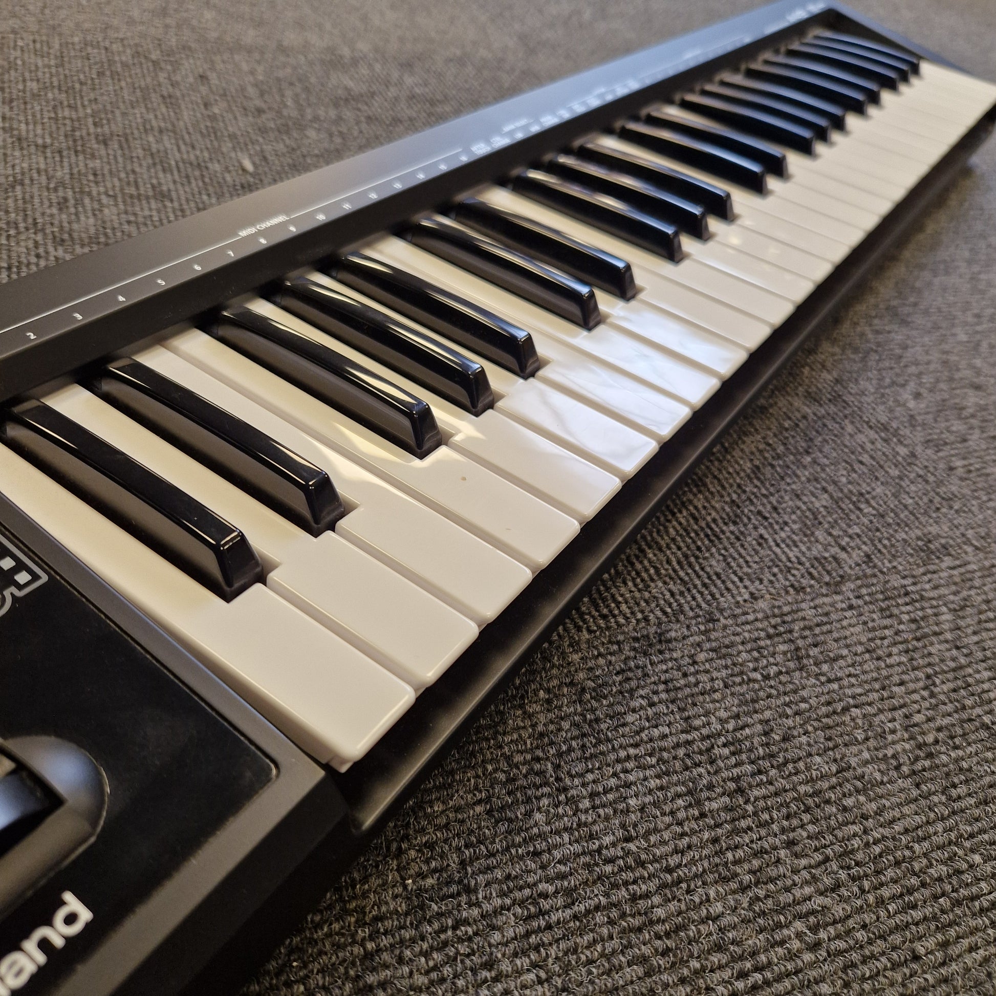Roland A-49 MIDI Keyboard Close-up of a keyboard with black and white keys on a textured surface