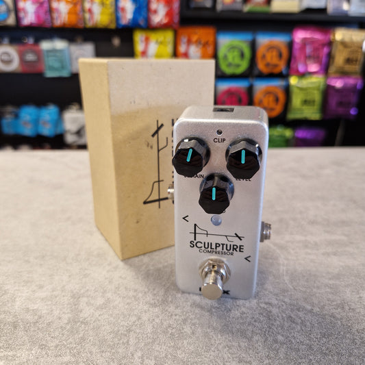 Nux NCP-2 Guitar effects pedal on a gray surface with colorful boxes in the background