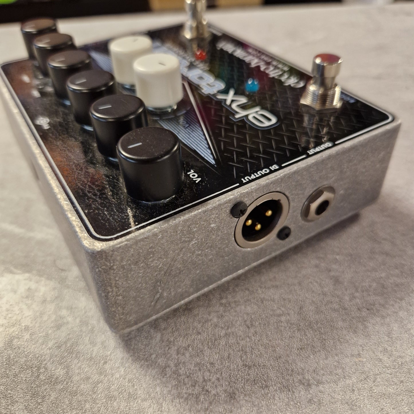 Pre-Owned Electro-Harmonix Close-up of a guitar effects pedal with visible branding on a grey surface.