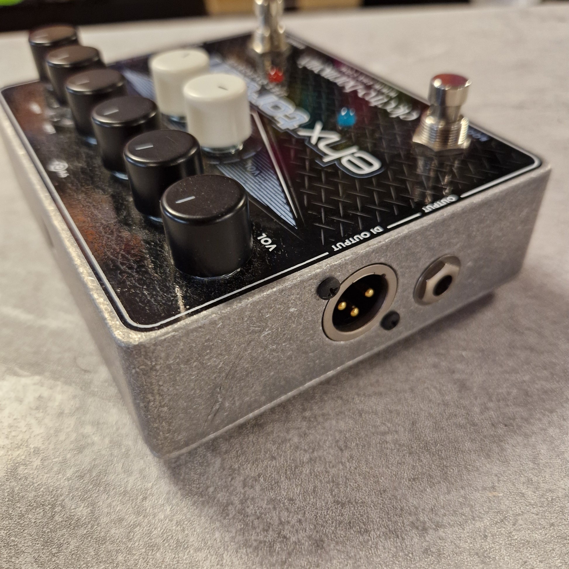 Pre-Owned Electro-Harmonix Close-up of a guitar effects pedal with visible branding on a grey surface.