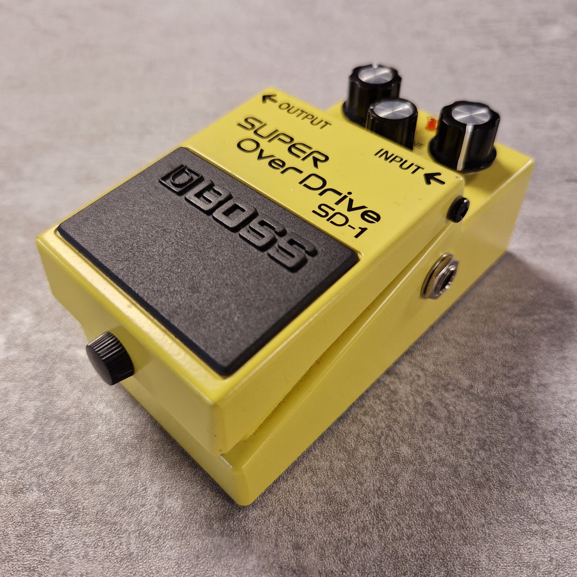 Pre-Owned Boss Yellow Boss Super OverDrive SD-1 guitar effects pedal on a grey background