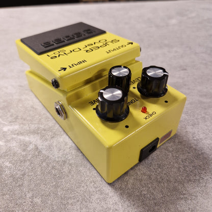 Pre-Owned Boss Yellow guitar effects pedal with knobs on a grey surface
