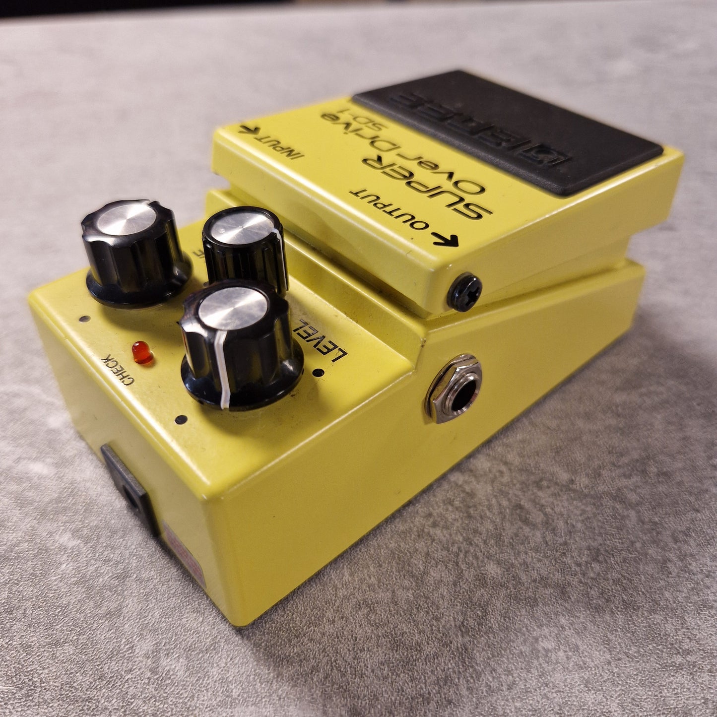 Pre-Owned Boss Yellow guitar effects pedal with control knobs on a grey surface