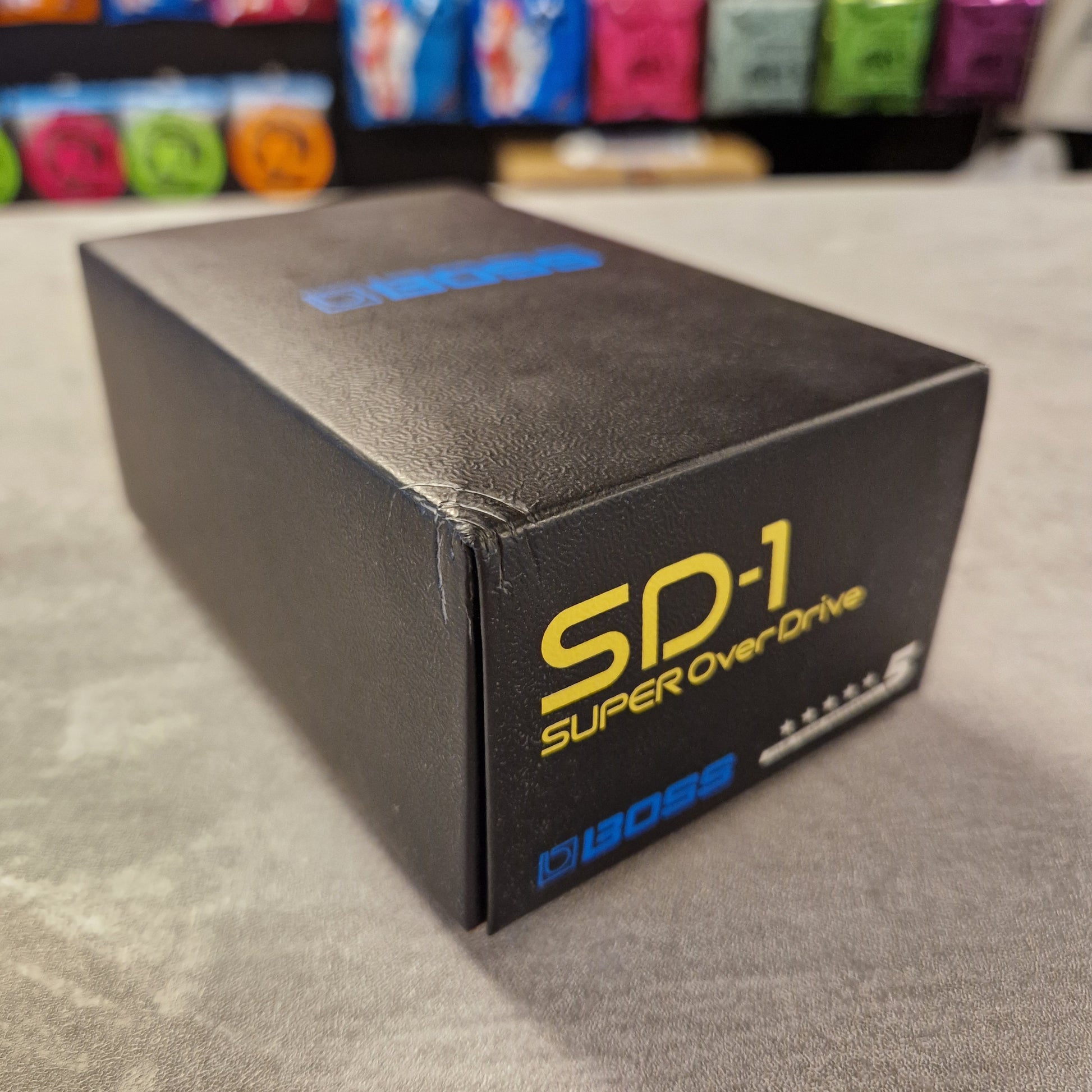 Pre-Owned Boss Black box with 'Super Overload' branding on a grey surface