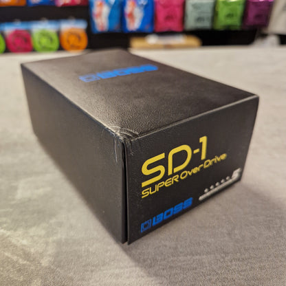 Pre-Owned Boss Black box with 'Super Overload' branding on a grey surface