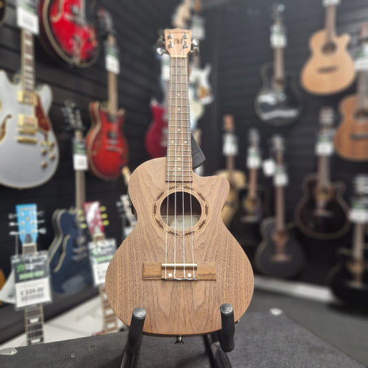 Pre-Owned Tanglewood Small wooden guitar held against a background of various guitars