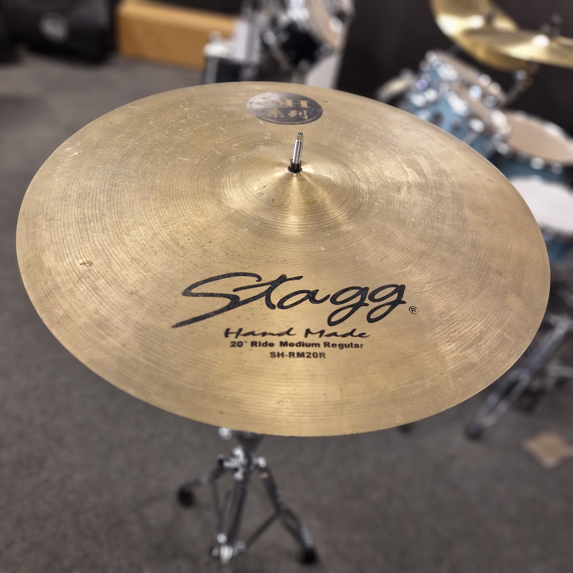 Pre-Owned Stagg Close-up of a Stagg cymbal with a blurred drum set in the background
