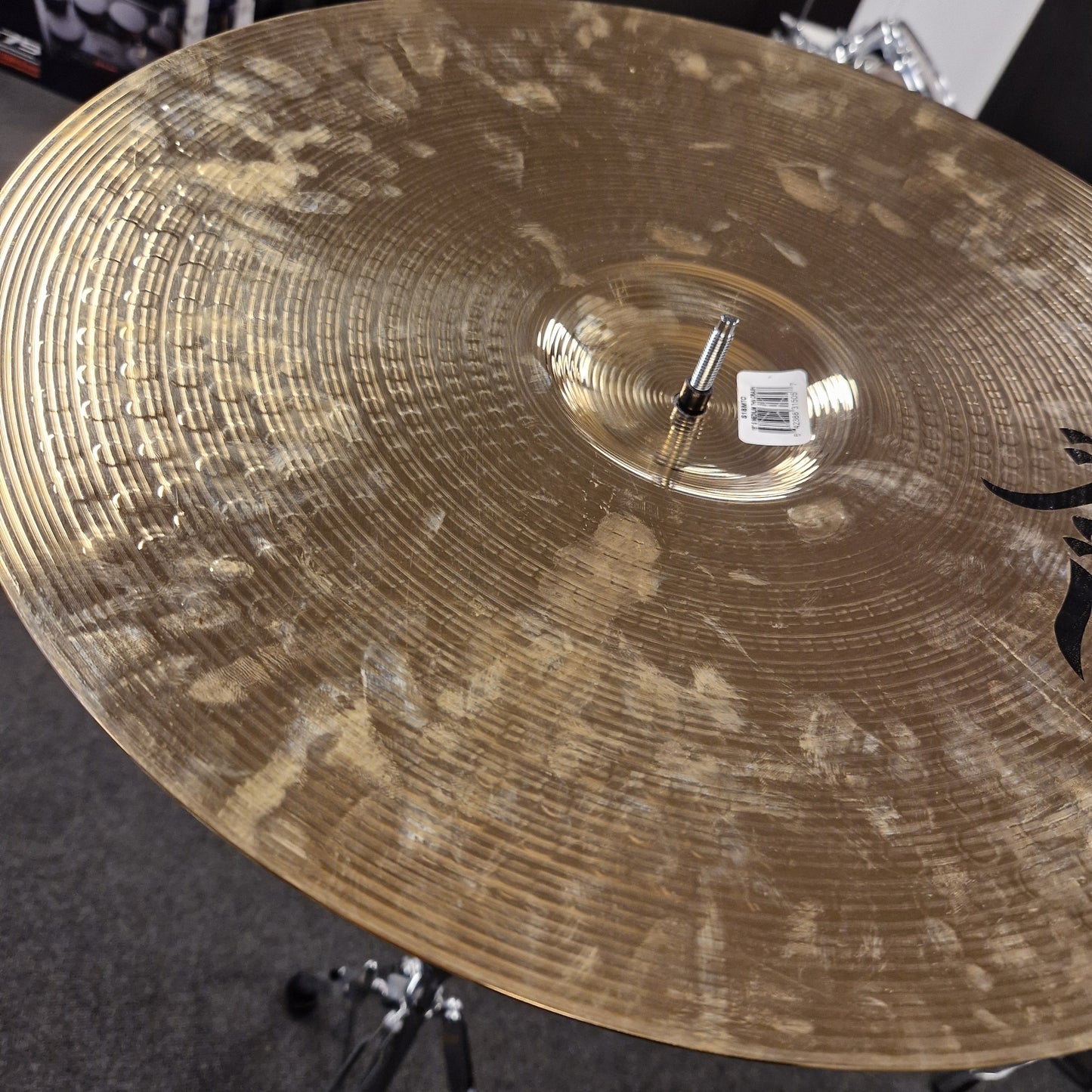 Pre-Owned Zildjian cymbal with a blurred background Close-up of a used cymbal with visible wear and a brand logo.