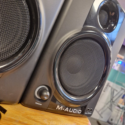 Pre-Owned M-Audio AV40 Studio Monitors Close-up of a M-Audio audio interface with speaker drivers on a wooden surface.