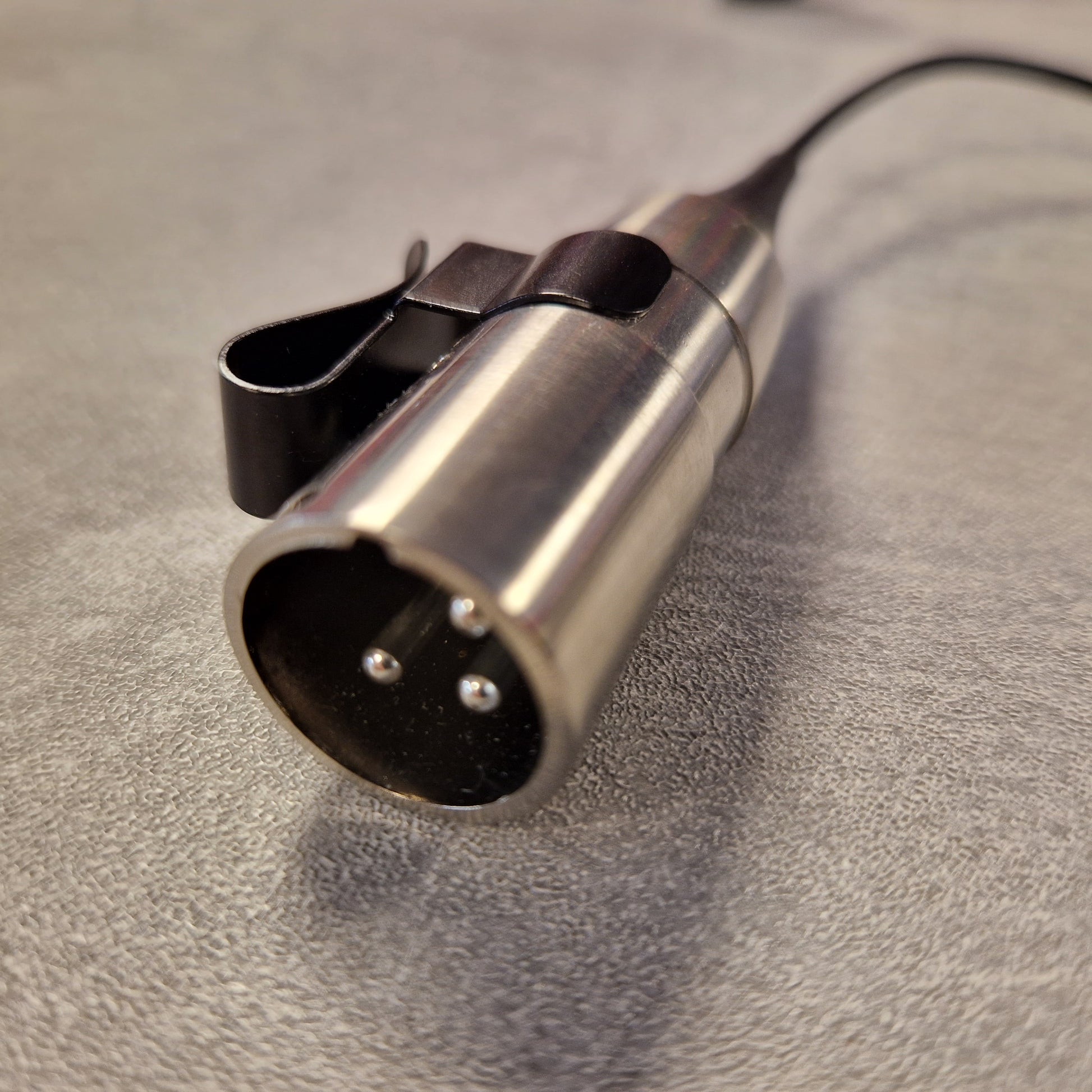 Pre-Owned Shure WH20XLR Headset Microphone - XLR Metallic microphone connector on a textured surface