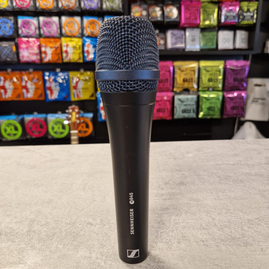 Pre-Owned Sennheiser E935 Sennheiser microphone on a carpeted floor with colourful boxes in the background