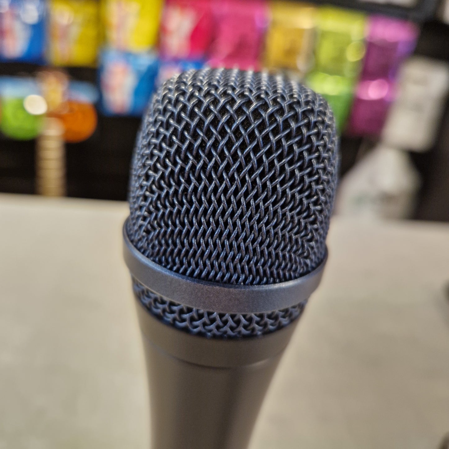 Pre-Owned Sennheiser E935 Close-up of a microphone with colourful items in the background