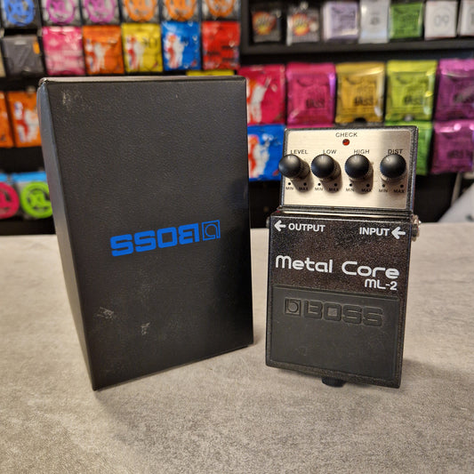 Pre-Owned Boss ML-2 Boss metal core ML-2 guitar effects pedal on a gray surface with colorful boxes in the background.