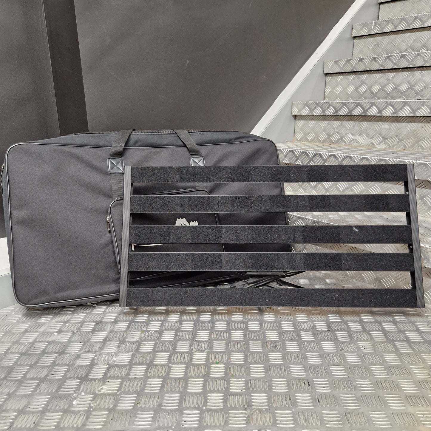 Pre-Owned Palmer Gray bag with black straps against a textured wall