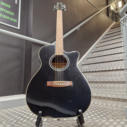 Pre-Owned Cruiser Black acoustic guitar on a stand with a patterned floor in the background