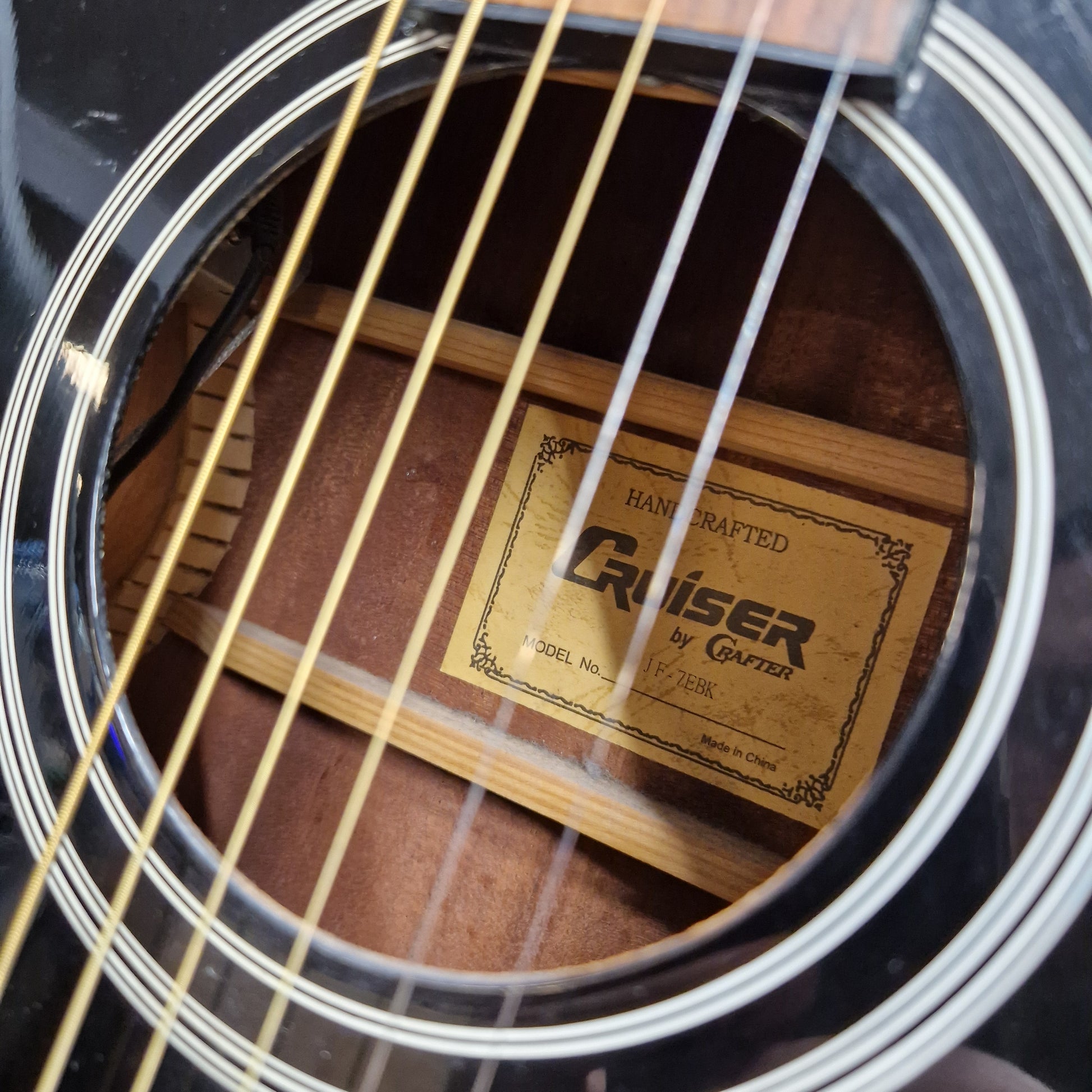 Pre-Owned Cruiser Close-up of a guitar's soundhole with a Rainer by Greiner label.