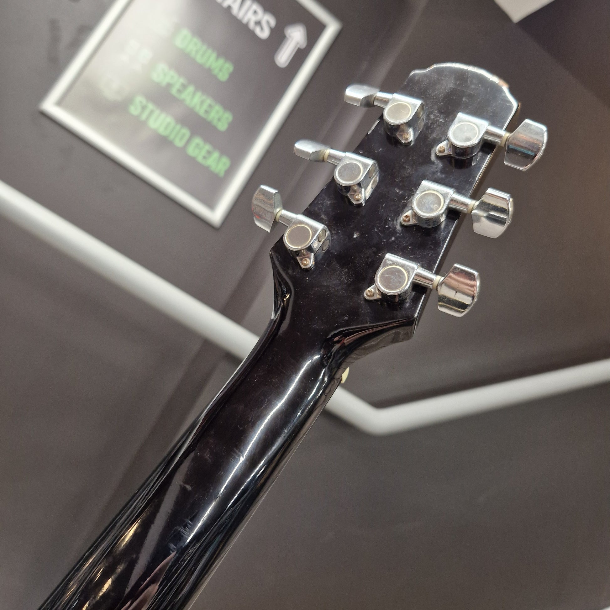 Pre-Owned Cruiser Close-up of a guitar headstock with tuning pegs on a blurred background
