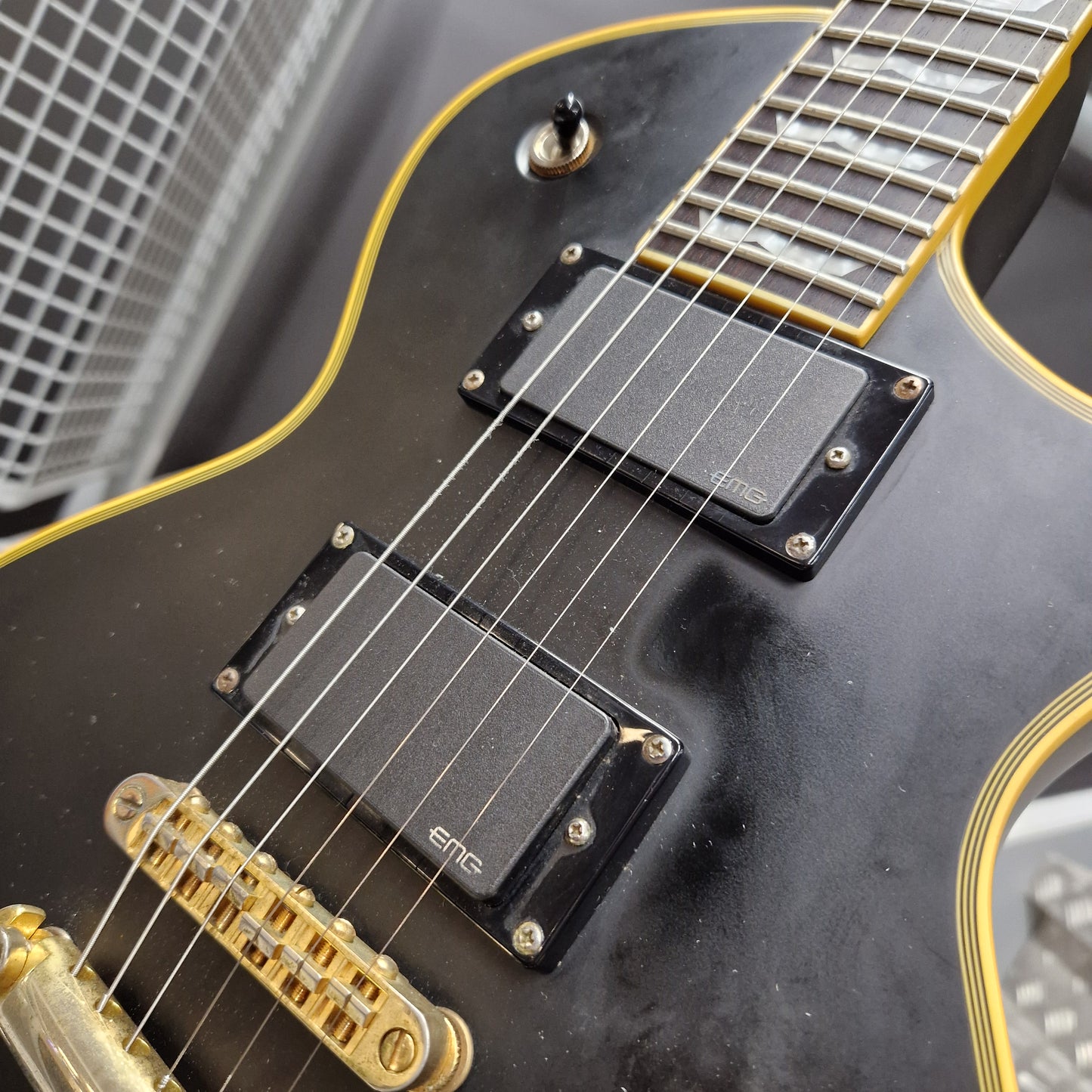 Pre-Owned ESP Close-up of a black electric guitar with gold hardware on a blurred background