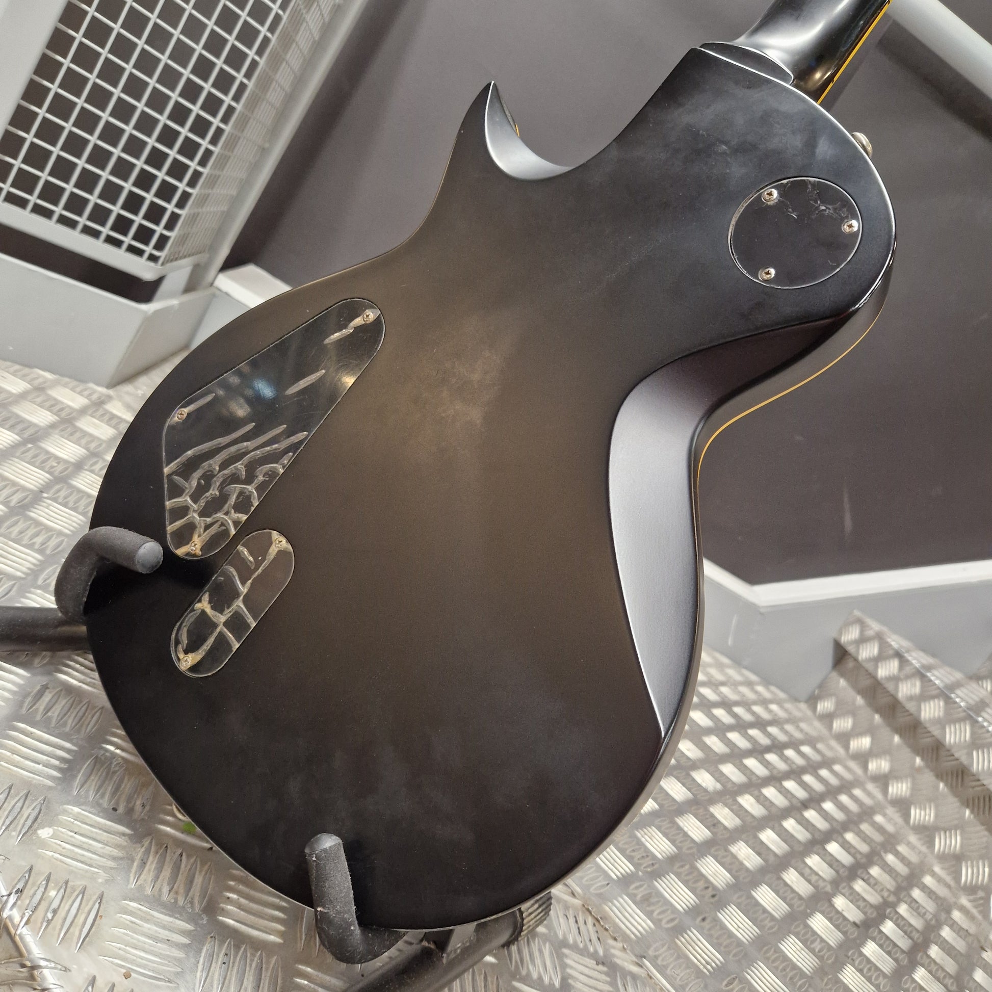 Pre-Owned ESP Black electric guitar on a stand with a metallic floor background