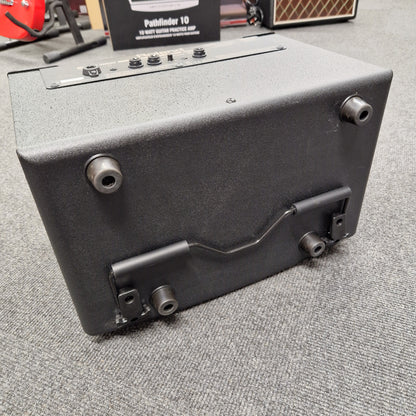 Pre-Owned Roland Guitar amplifier on a gray surface with visible controls and speaker.