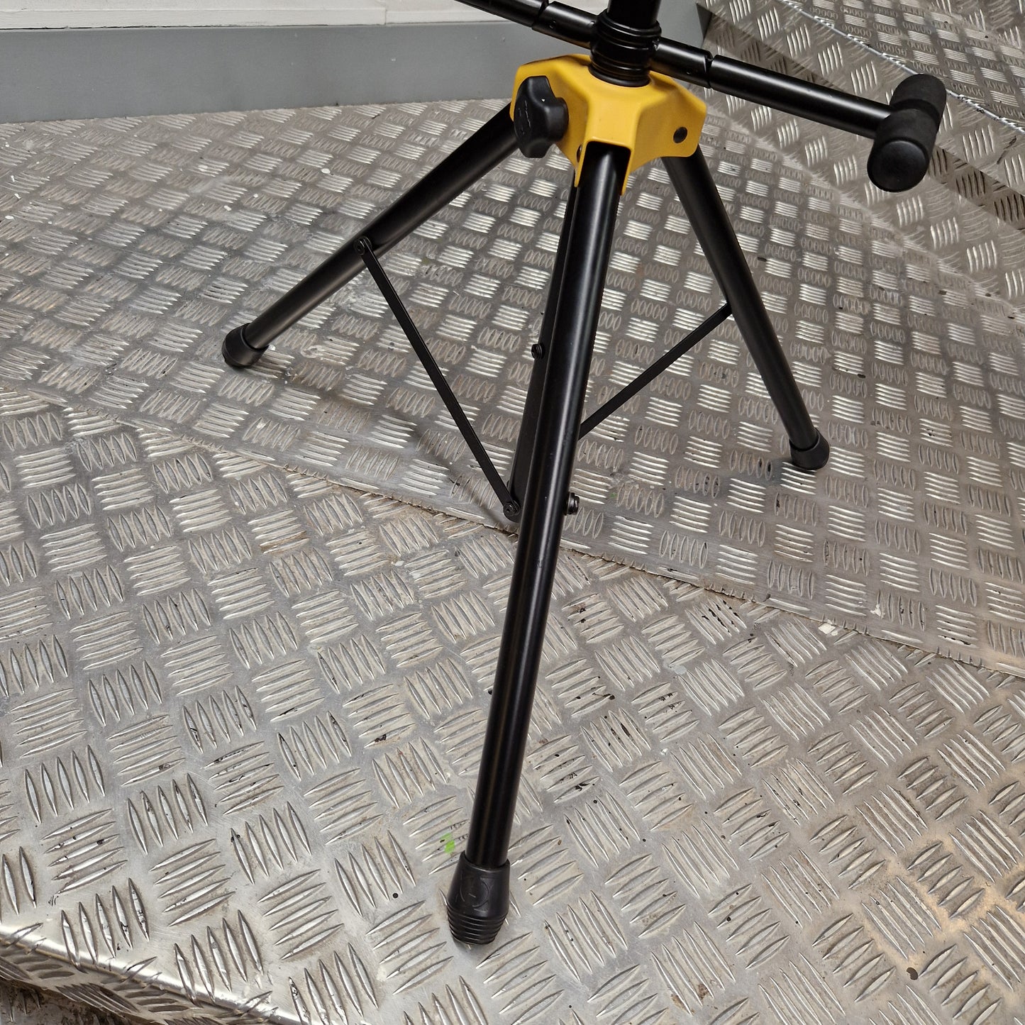 Pre-Owned Hercules Black metal stand with yellow base on a textured metal surface