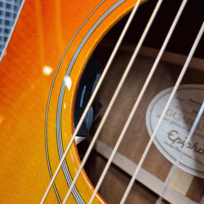 Pre-Owned Epiphone Close-up of an orange acoustic guitar with a visible brand label.