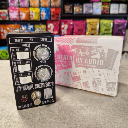 Pre-Owned Death by Audio Guitar effects pedal with 'Space Bender' branding next to its packaging in a store setting.