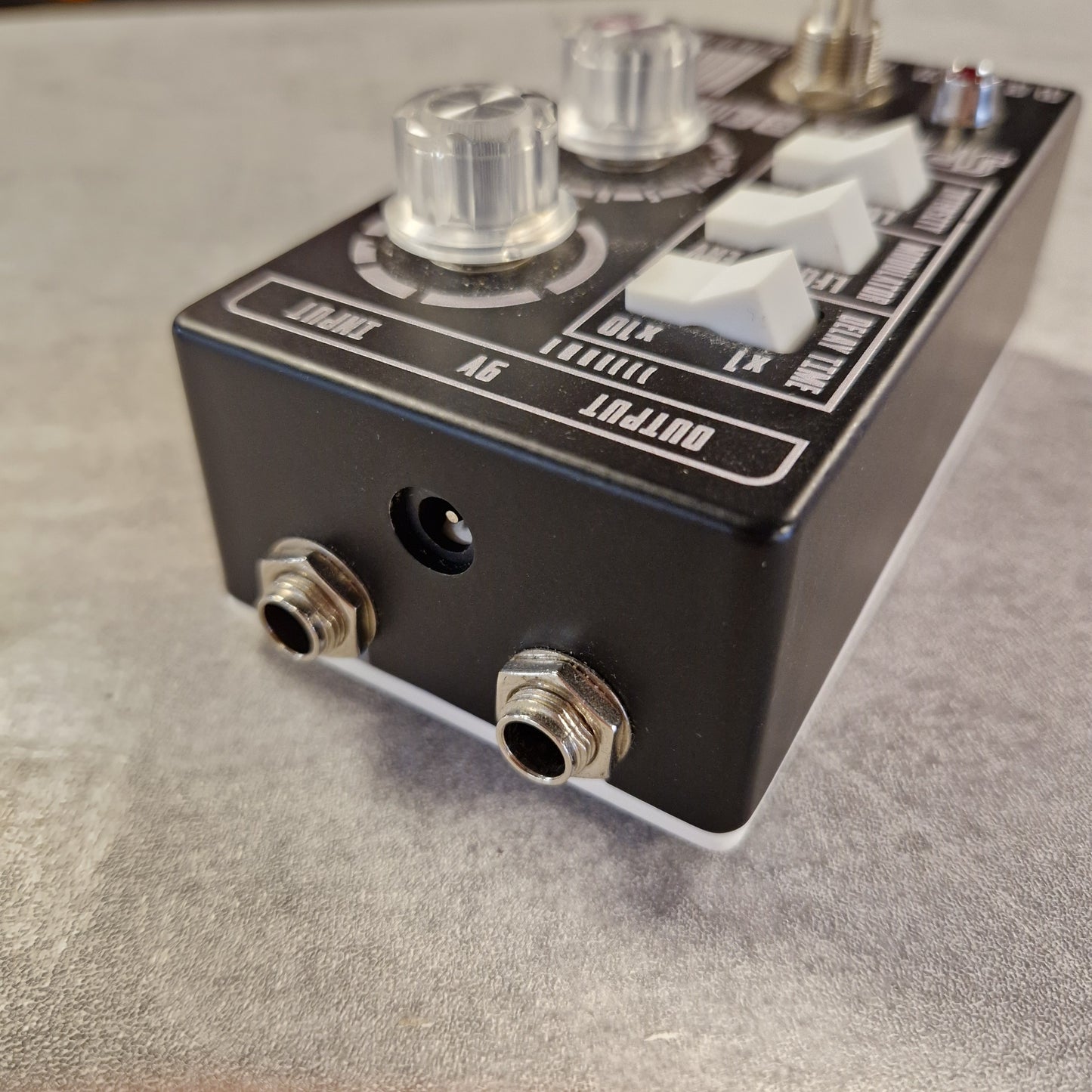 Pre-Owned Death by Audio Guitar effects pedal with knobs and jacks on a gray surface